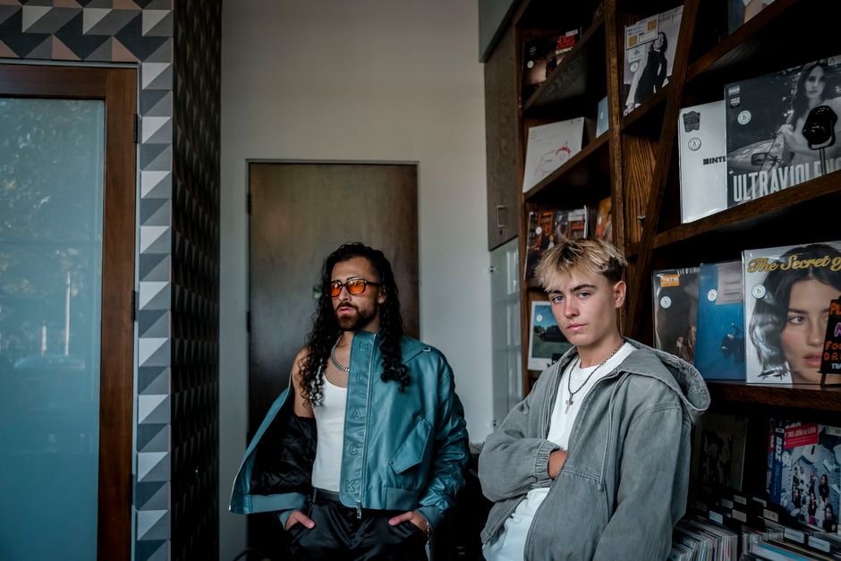 Two trendy young adults pose fashionably in a modern record store, showcasing urban culture.