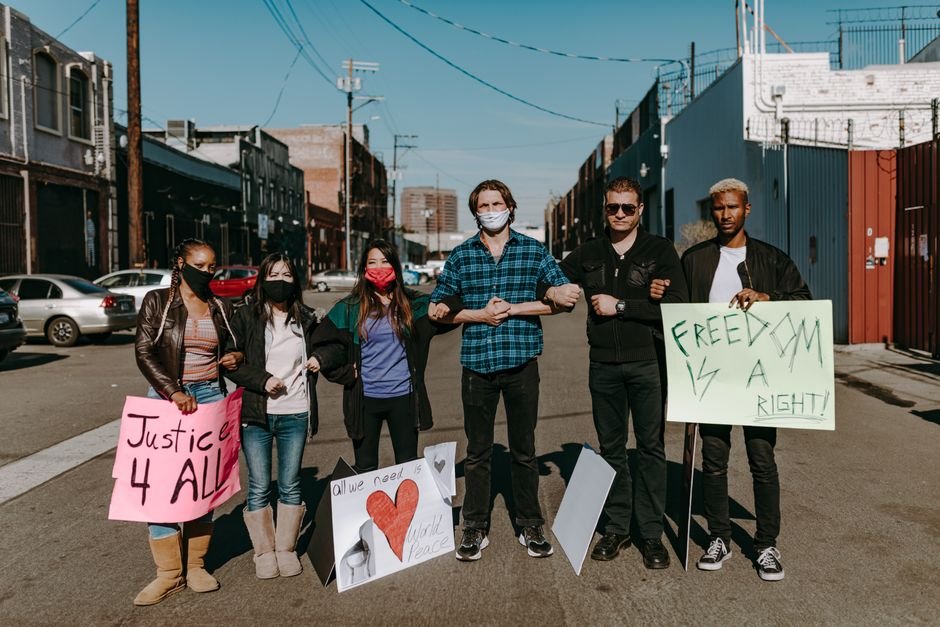 A diverse group of people holding signs for justice and freedom during a daytime protest.