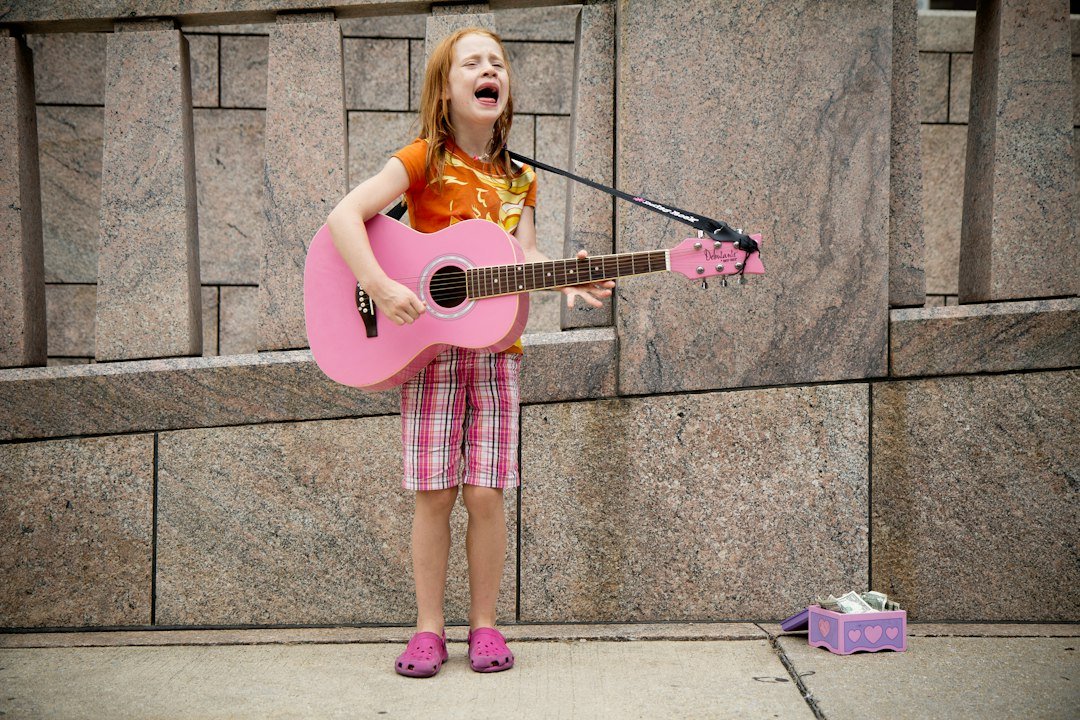 girl playing guitar near wall