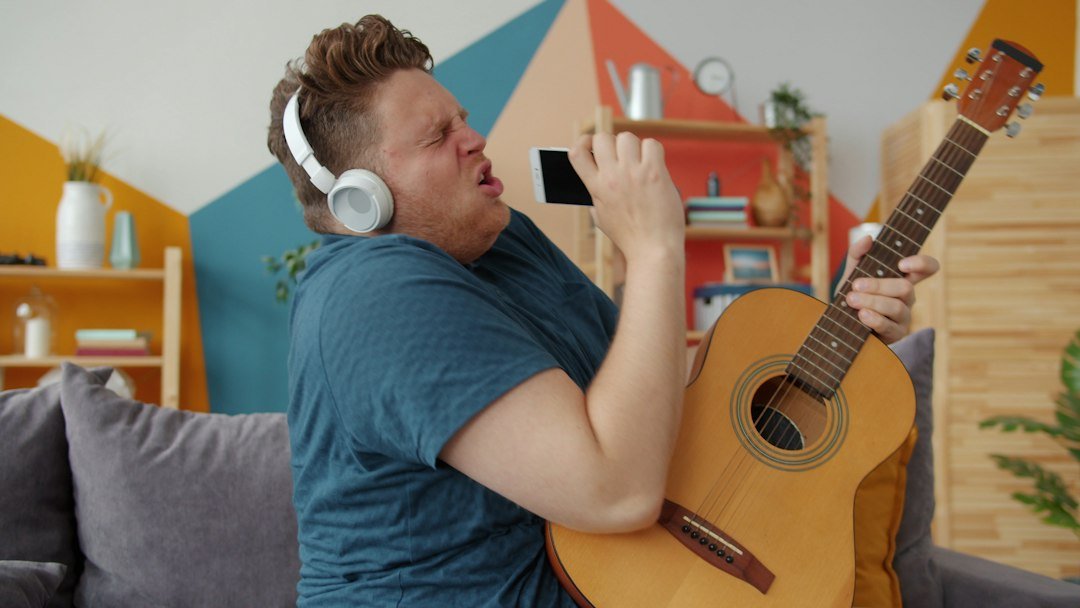 Man singing and playing guitar with headphones on